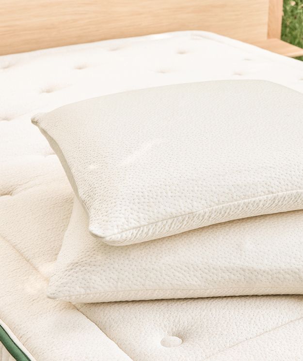 Almofadas de látex natural Kipli colocadas sobre um colchão ecológico de látex, exemplificando uma roupa de cama saudável e sustentável.