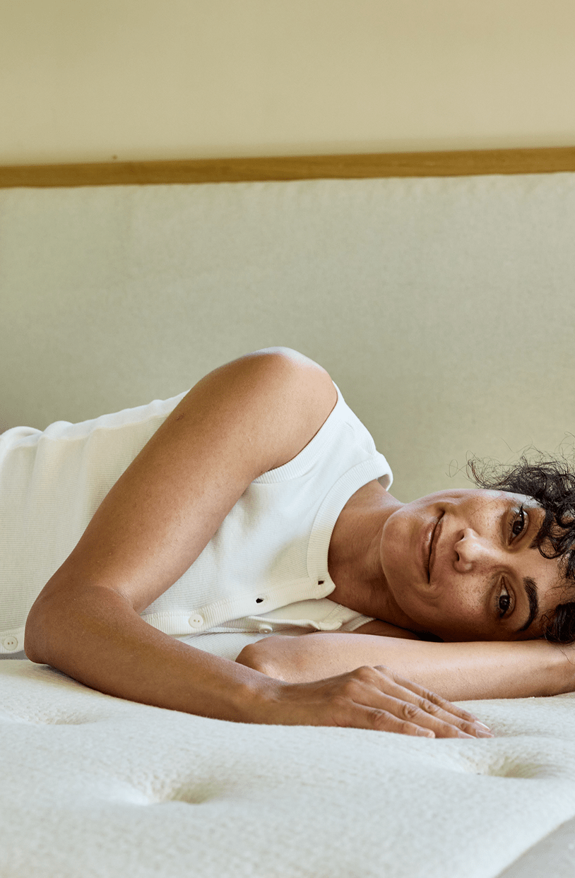 Mulher deitada num colchão de látex natural Kipli, ilustrando o conforto e o apoio de uma roupa de cama ecológica.